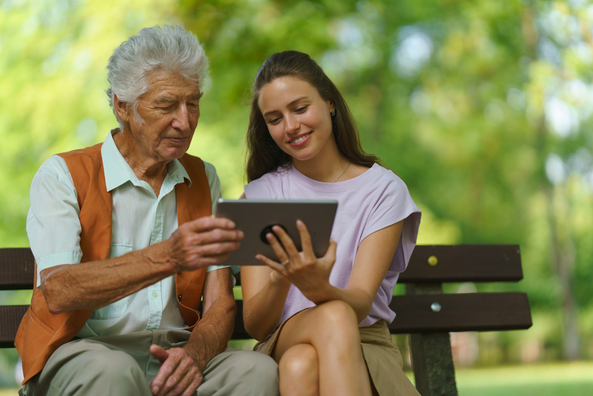 Caregiver helping senior man to shop online on tablet. The risk of online shopping scams targeting